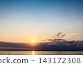 setting sun in dark sky over low clouds and sea 143172308