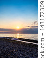 setting sun over clouds, sea and pebble beach 143172309