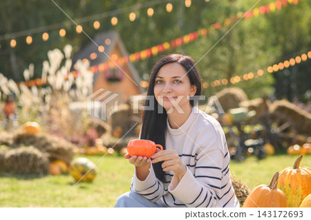 Woman enjoying hot drink at cozy outdoor pumpkin patch in autumn Woman enjoying hot drink at cozy outdoor pumpkin patch in autumn 143172693