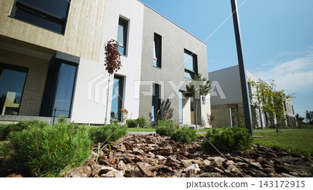 Modern townhouses exterior with minimalist architecture and green landscaping under a clear blue sky Modern townhouses exterior with minimalist architecture and green landscaping under a clear blue sky 143172915