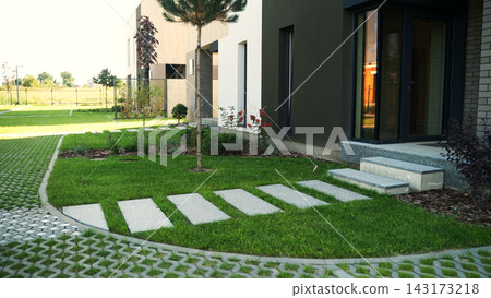 Modern townhouses with green garden landscaping, stone path leading to residential entrance, urban development 143173218