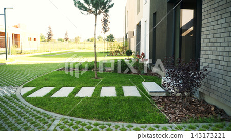 Contemporary building exterior with modern landscaping, green lawn, permeable pavers, and stepping stone path design Contemporary building exterior with modern landscaping, green lawn, permeable pavers, and stepping stone path design 143173221