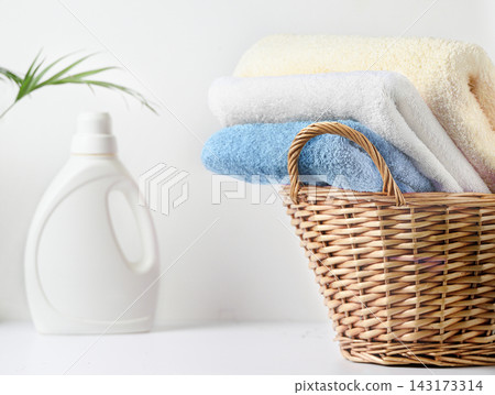 Stacked pastel towels in wicker basket beside laundry detergent bottle on white countertop linen set Stacked pastel towels in wicker basket beside laundry detergent bottle on white countertop linen set 143173314