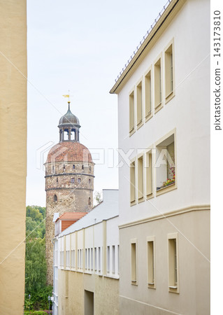 Historic round stone tower with red tiled dome and cupola seen between old town buildings Historic round stone tower with red tiled dome and cupola seen between old town buildings 143173810