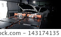 EV car service. Electric vehicle battery pack being serviced or inspected in automotive workshop. Large battery modules and high voltage components. Modern EV power systems. Lithium ion NMC NCA or LFP 143174135