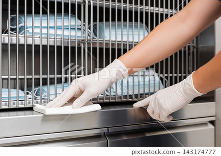 A professional cleaning a stainless steel medical cabinet filled with stacks of face masks A professional cleaning a stainless steel medical cabinet filled with stacks of face masks 143174777