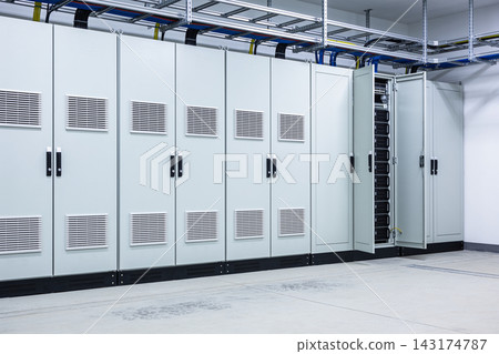 Industrial server room with rows of grey metal cabinets and overhead cable management systems Industrial server room with rows of grey metal cabinets and overhead cable management systems 143174787