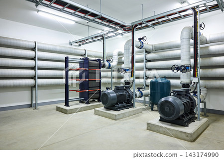 Industrial mechanical room featuring high-efficiency water pumps and heat exchanger equipment Industrial mechanical room featuring high-efficiency water pumps and heat exchanger equipment 143174990