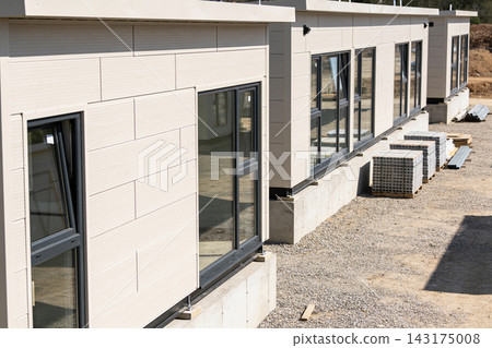 Modern modular housing units under construction on a gravel site with concrete foundations Modern modular housing units under construction on a gravel site with concrete foundations 143175008