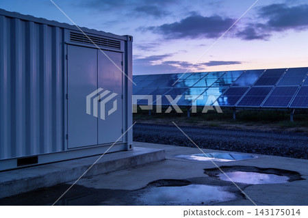 Industrial battery storage container next to a solar panel field at dusk in the countryside Industrial battery storage container next to a solar panel field at dusk in the countryside 143175014