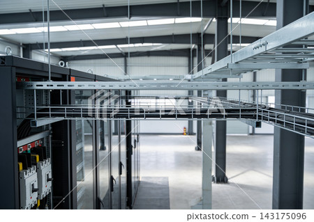 Industrial electrical control cabinets with overhead cable management systems in a large warehouse Industrial electrical control cabinets with overhead cable management systems in a large warehouse 143175096