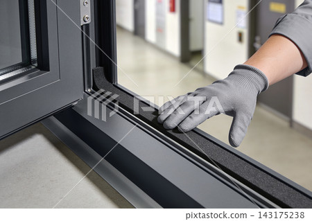 Professional technician installing a black rubber weather seal on a modern aluminum window frame Professional technician installing a black rubber weather seal on a modern aluminum window frame 143175238