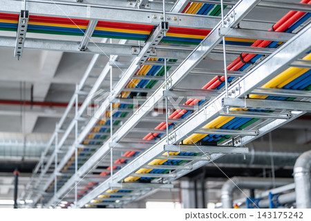 Industrial cable trays with colorful electrical wiring installed on a modern factory ceiling Industrial cable trays with colorful electrical wiring installed on a modern factory ceiling 143175242