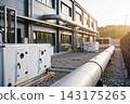 Industrial building exterior with large HVAC ventilation units and metal piping at sunset 143175265