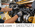 Mechanic performing maintenance on a heavy construction machinery engine in a workshop setting 143175273