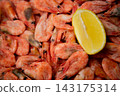 A close-up of frozen shrimps with a pronounced layer of frost, a bright slice of lemon is located on the right side of the frame. The concept: an emphasis on frost crystals, a contrast with the 143175314