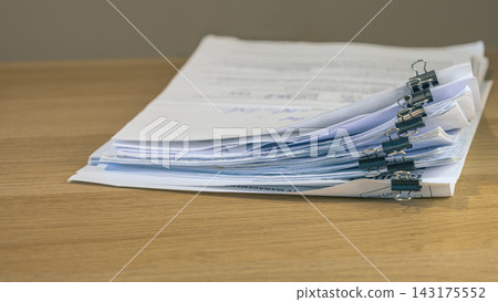 Stacked business documents secured with binder clips Stacked business documents secured with binder clips 143175552