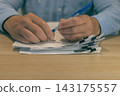 Office worker hands holding pen over stacked documents 143175557