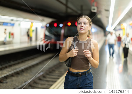 Young woman standing on metro station platform waiting for train Young woman standing on metro station platform waiting for train 143176244