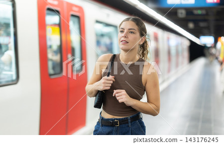 Young woman standing on metro station platform waiting for train 143176245