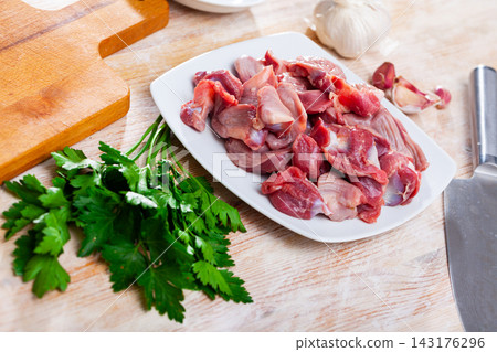 Raw chicken gizzards before cooking on table with greens Raw chicken gizzards before cooking on table with greens 143176296