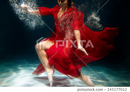 Cinematic shot of poised red dressed performer amid bubbles Cinematic shot of poised red dressed performer amid bubbles 143177012