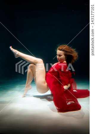 Woman dressed in red immersed in shadowy pool scene with dramatic lighting Woman dressed in red immersed in shadowy pool scene with dramatic lighting 143177101