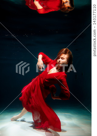 Underwater scene features poised dancer in flowing red costume Underwater scene features poised dancer in flowing red costume 143177110