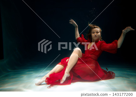 Elegant young woman in flowing dress near luminous water Elegant young woman in flowing dress near luminous water 143177200