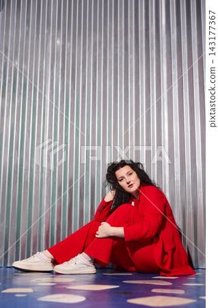 Serene female figure in vibrant attire standing near shiny wall Serene female figure in vibrant attire standing near shiny wall 143177367