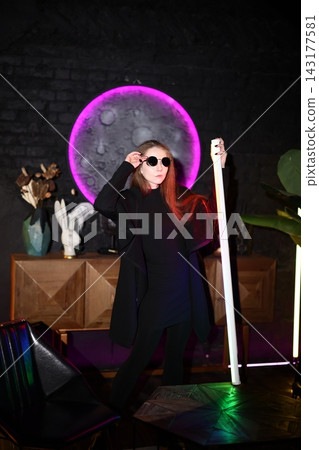 Woman with dark glasses models dramatically using neon lighting effects Woman with dark glasses models dramatically using neon lighting effects 143177581
