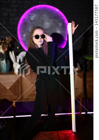 Female entertainer stands confidently near illuminated display Female entertainer stands confidently near illuminated display 143177587