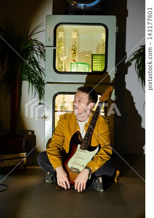 An artist finetunes his electric instrument during late evening hours An artist finetunes his electric instrument during late evening hours 143177601