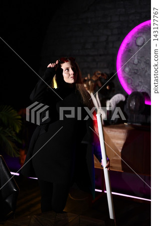 Black dressed woman utilizes red glasses amidst luminous backdrop Black dressed woman utilizes red glasses amidst luminous backdrop 143177767