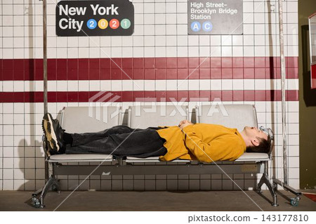 Lonely commuter taking break beneath tiled station sign Lonely commuter taking break beneath tiled station sign 143177810