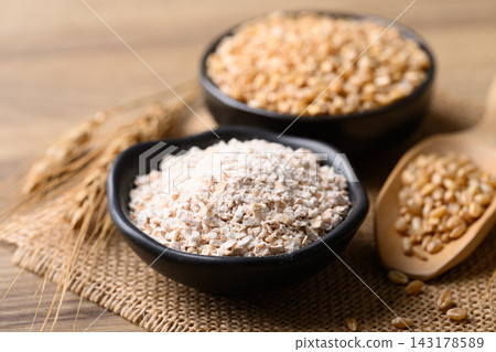 Whole wheat flour and dried wheat grain in a black bowl, food ingredient 143178589