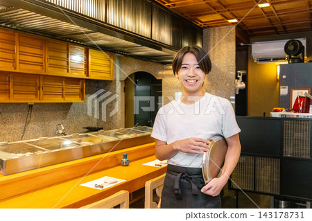 A young male part-timer working at a sushi restaurant A young male part-timer working at a sushi restaurant 143178731