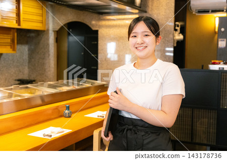 Female university student working at a sushi restaurant Female university student working at a sushi restaurant 143178736
