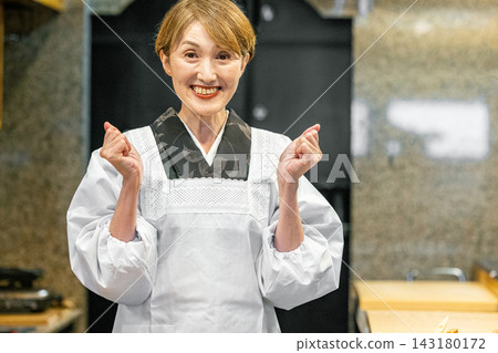 一位資深女老闆站在居酒屋（日式酒吧）的櫃檯後面 143180172