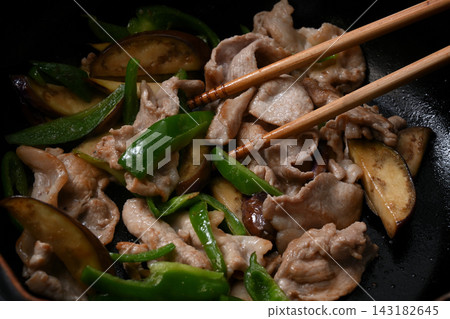 Eggplant, green peppers and pork being fried in a frying pan Eggplant, green peppers and pork being fried in a frying pan 143182645