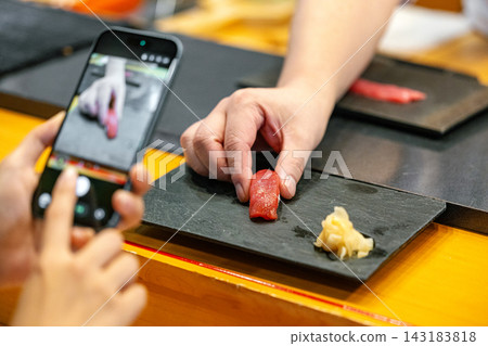 一位女士用智慧型手機拍照，以紀念她造訪高級壽司店的經歷。 143183818