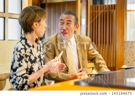 A senior couple and the chef at a sushi restaurant A senior couple and the chef at a sushi restaurant 143184075