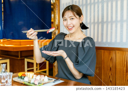 一位年輕女子獨自在壽司店享用午餐 143185423