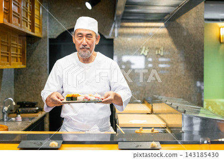 A senior male sushi chef holding a sushi plate A senior male sushi chef holding a sushi plate 143185430