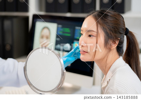 Asian woman patient looking in mirror with anxiety and checking skin face problem. Asian woman patient looking in mirror with anxiety and checking skin face problem. 143185888