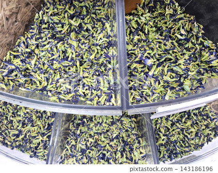 Vibrant blue and green dried butterfly pea flowers in large display containers, perfect for herbal tea and natural food coloring. Vibrant blue and green dried butterfly pea flowers in large display containers, perfect for herbal tea and natural food coloring. 143186196