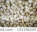 Close view of raw candlenut seeds featuring pale beige color and oily surface texture ideal for traditional cuisine recipes and culinary preparation. 143186204