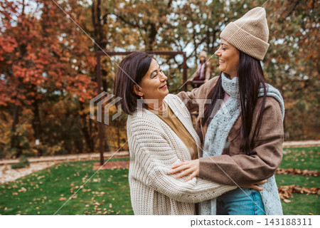 Mature daughter with older mom standing in the middle of autumn park. Mature daughter with older mom standing in the middle of autumn park. 143188311