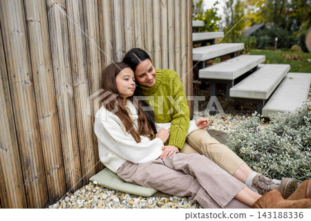 Portrait of beautiful mother with young daughter, sitting together and embracing. Portrait of beautiful mother with young daughter, sitting together and embracing. 143188336