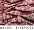 A wrinkled and folded fabric with a pink and white plaid pattern 143189043